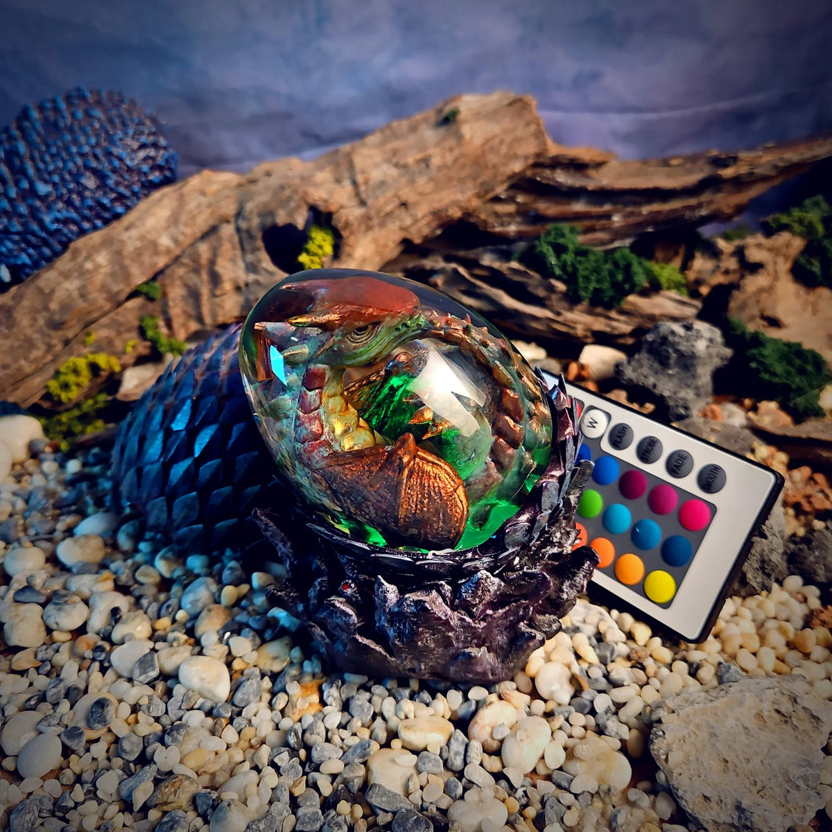 Bronze baby dragon egg lamp glowing green on a dark scaled cradle