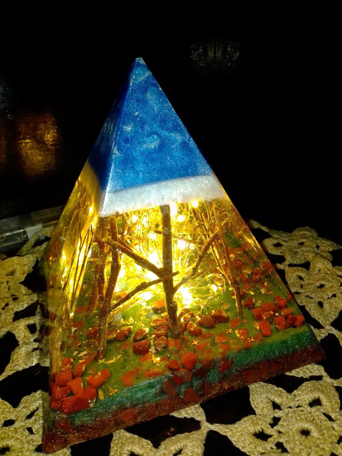 Forest resin pyramid lamp with red stone chips and blue tip, angled view