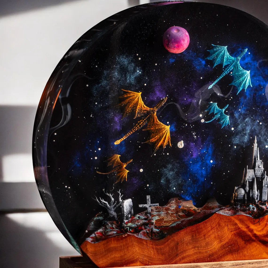 Close-up of orange and teal dragons, pink moon and castle