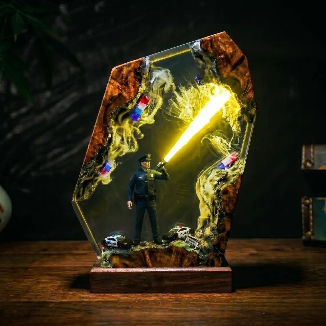 Police officer resin lamp glowing yellow, patrol cars at the base