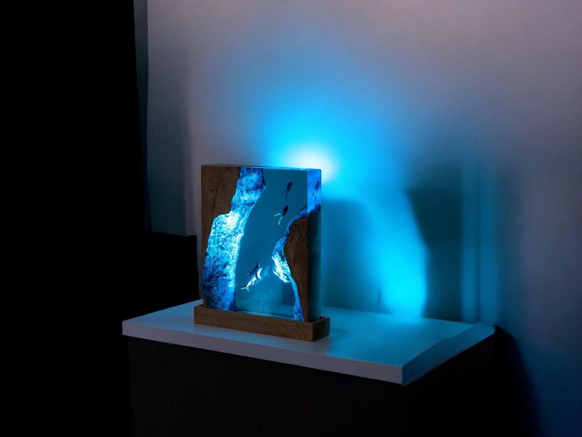 Shark resin lamp casting blue light on a wall at night