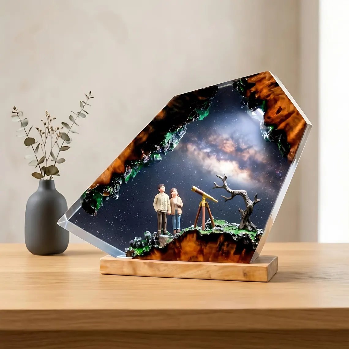 Stargazing couple resin lamp beside a vase on a wood table