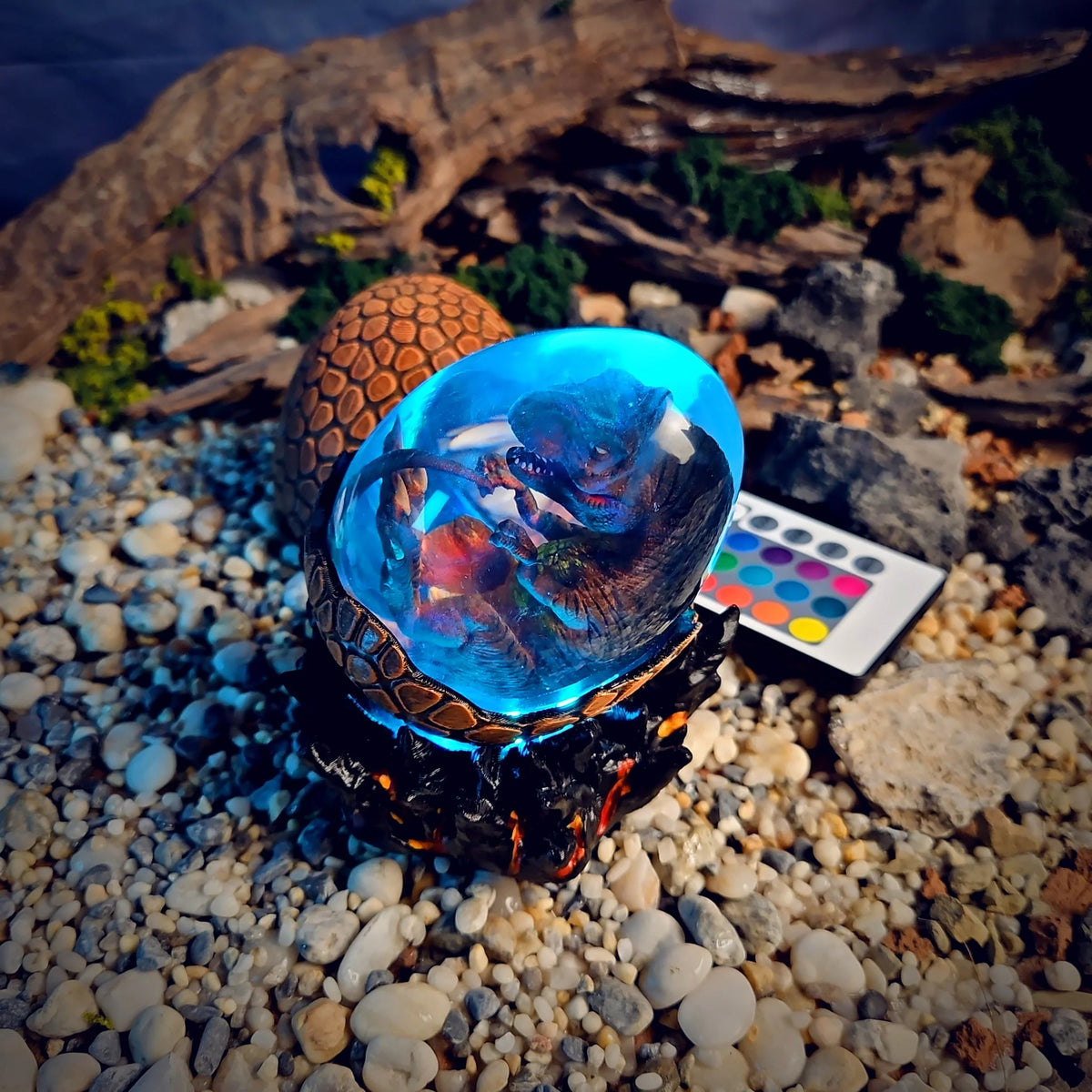 Dinosaur egg lamp glowing blue on its black lava base