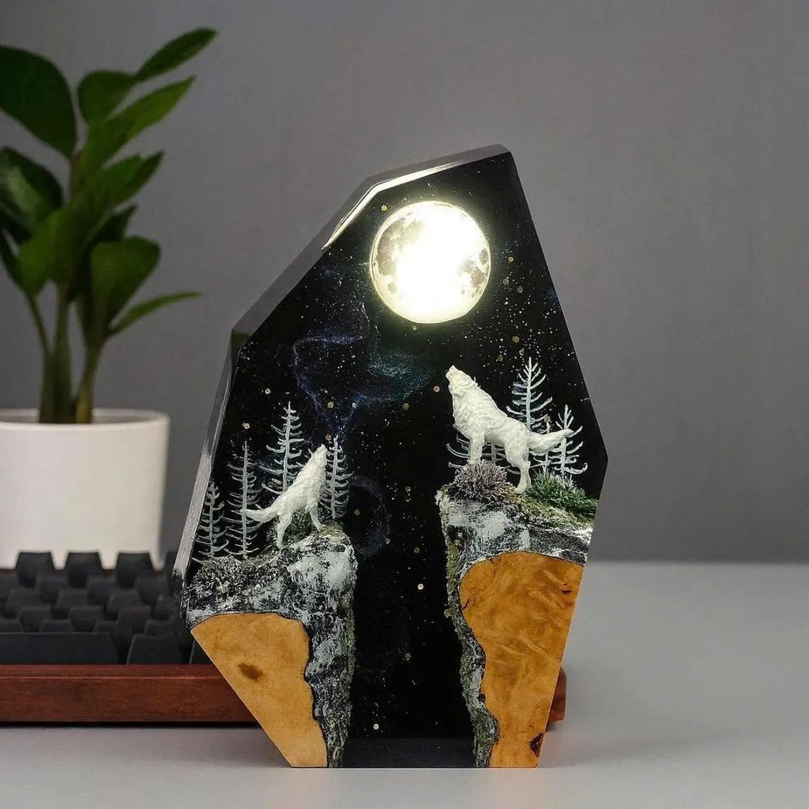 Wolf moon resin lamp on a desk beside a plant